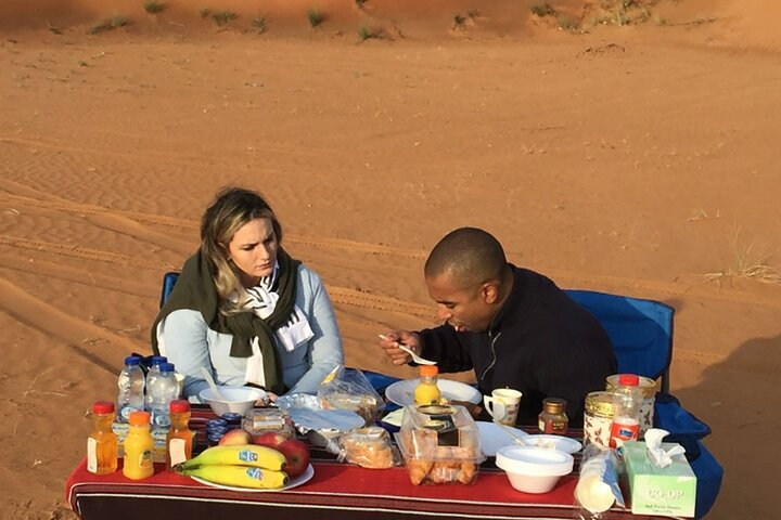 Savor a delicious Bedouin-style breakfast in the serene Dubai desert surrounded by stunning red dunes offering a unique blend of culture and adventure after an exciting safari experience.